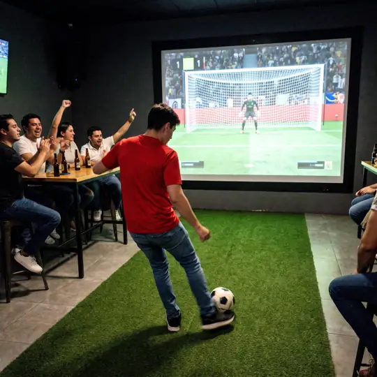 Simulador de penales con pantalla y césped en un bar