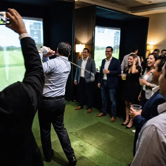 Ejecutivo juega en un simulador de golf durante un evento corporativo en hotel