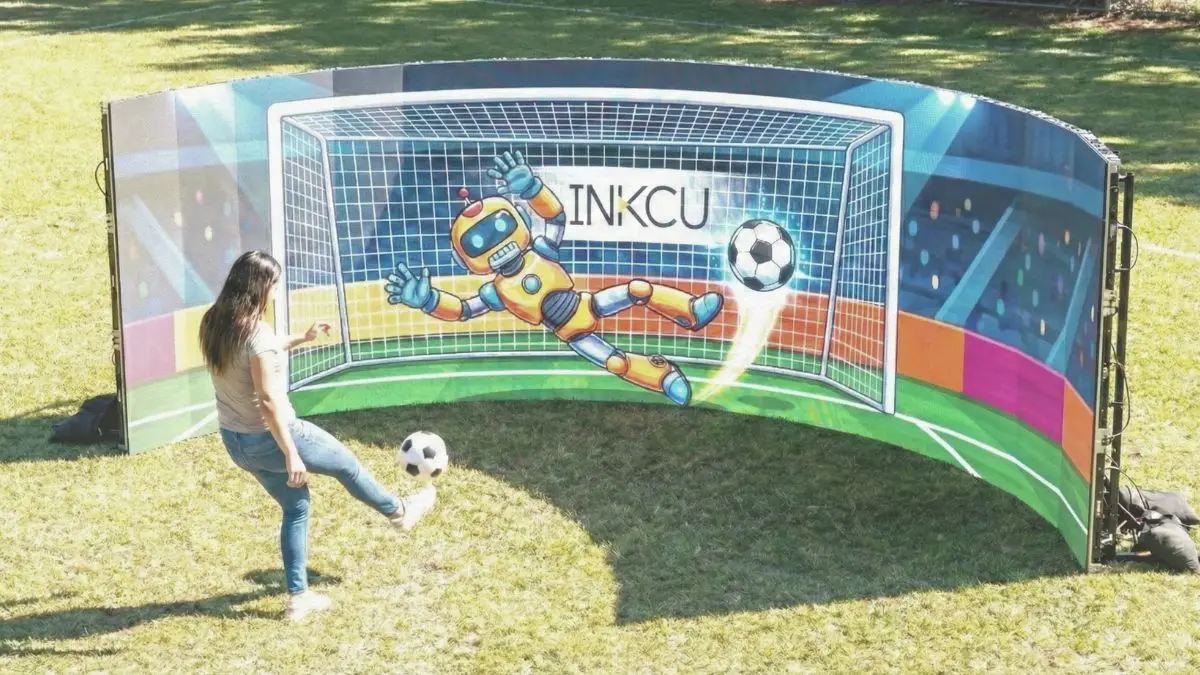Mujer patea un balón hacia una pantalla curva interactiva al aire libre